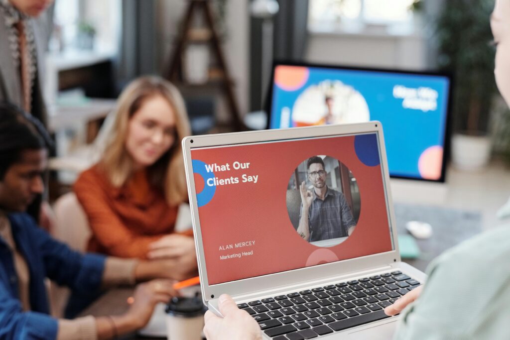 Diverse business team in a meeting analyzing client testimonial on laptop screen.